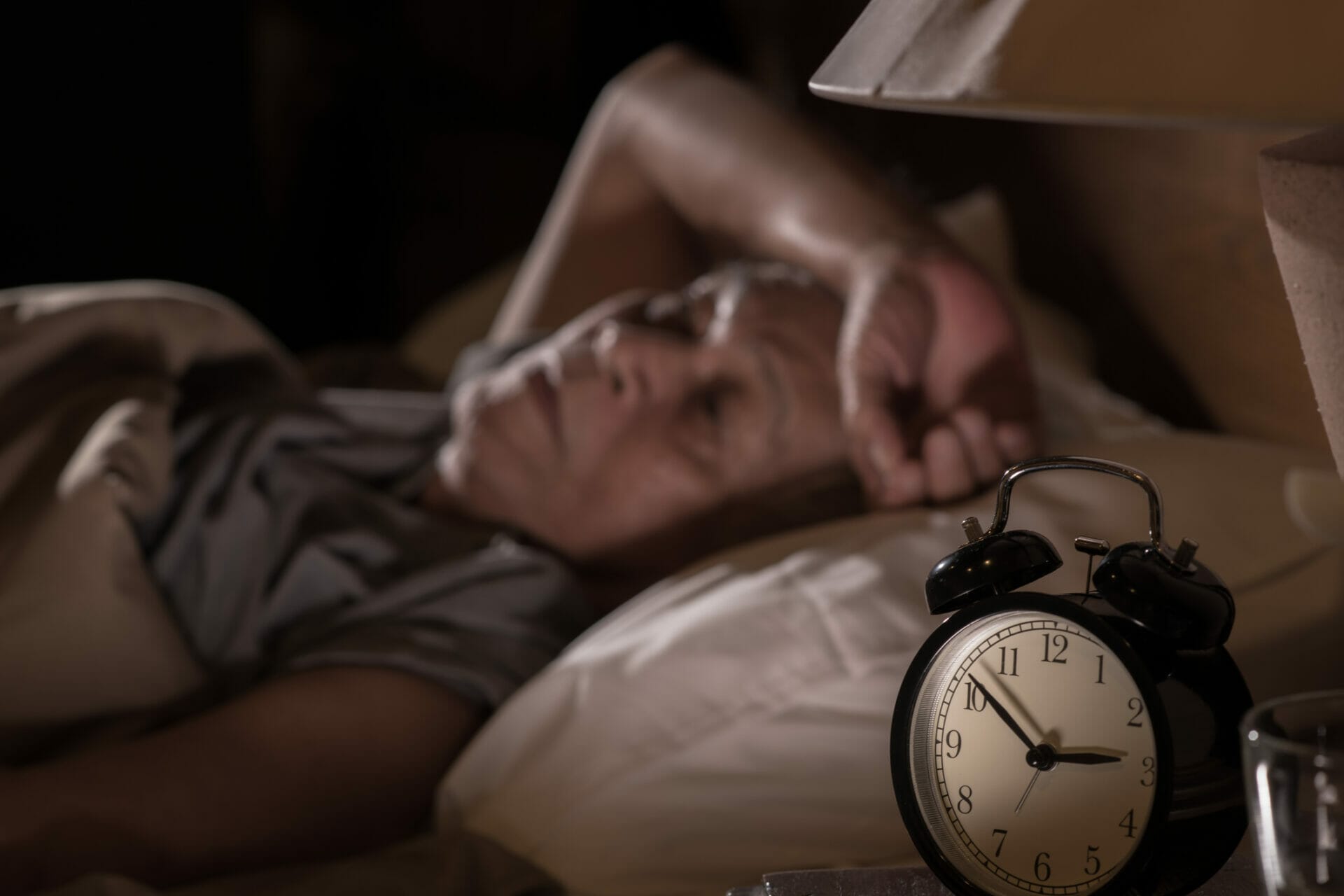 A senior man lying in bed cannot sleep from insomnia